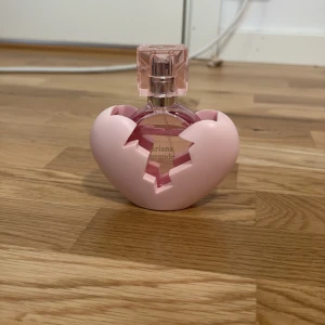 ariana grande parfym - Charmig parfym från Ariana Grande i en unik hjärtformad flaska med rosa detaljer. Flaskan har en avtagbar rosa hylsa och en fyrkantig, genomskinlig kork. Perfekt för den som älskar söta och romantiska dofter.