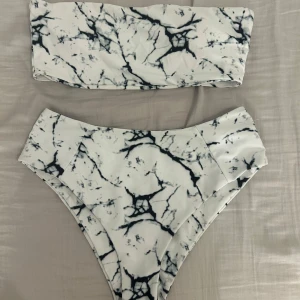 Marmormönstrad bikini - Snygg bikini med marmormönster i svart och vitt. Överdelen är en bandeau-modell och underdelen har hög midja