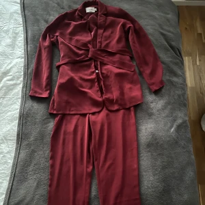 Vinröd kostym från NA-KD - Snygg vinröd kostym från NA-KD, defekter förekommer. Strl 34 i toppen och strl 36 i byxorna!