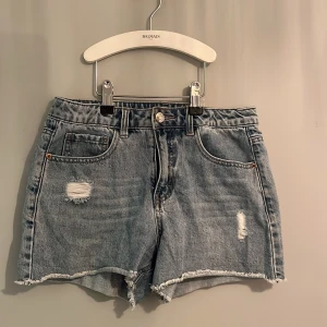 Blå jeansshorts från Lab Industries - Snygga blå jeansshorts från Lab Industries med slitna detaljer och fransig kant. Perfekta för en avslappnad stil. De har en klassisk femficksdesign