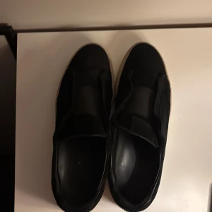 Svarta sneakers i mocka Arigato - Snygga svarta sneakers i mocka med en stilren design. Skorna har en vit sula som ger en fin kontrast och en modern look. Perfekta för en avslappnad stil.