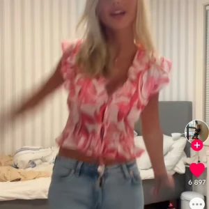 Röd och vit blommig blus - Säljer en söt blommig blus i rött och vitt med volangdetaljer. Blusen har korta ärmar och knytning framtill, vilket ger en romantisk touch. Perfekt för sommarens varma dagar! Helt oanvänd utan lapp första bilden är lånad säljer pga att den är för liten💕