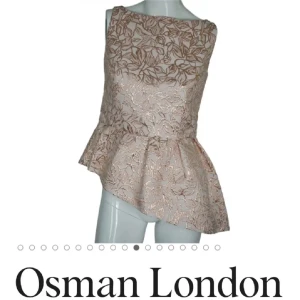 Ljusrosa blus från Osman London Peplum - Snygg ljusrosa peplum topp från Osman London med ett vackert blommigt mönster. Blusen har en asymmetrisk volangdetalj i nederkant och är ärmlös. Perfekt för en stilren look.