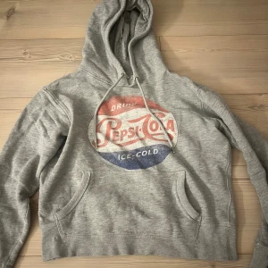 Grå hoodie med Pepsi-Cola tryck - Säljer en grå hoodie med ett retro Pepsi-Cola tryck i rött och blått. Den har en klassisk känguruficka och justerbar huva med snören. Pm för mer info 💕