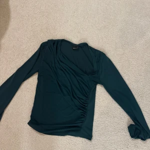 Mörkgrön omlottopp från Gina Tricot - Snygg mörkgrön omlottopp från Gina Tricot med långa ärmar.  Storlek Xs, Upplever att den passar en S också då jag vanligtvis är en S! 