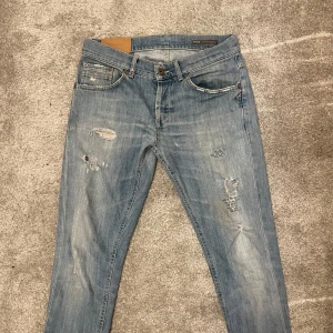 Ljusblå jeans från Dondup - Snygga ljusblå jeans från Dondup med slitna detaljer och en klassisk femficksdesign. Märkeslogga syns på baksidan.Jag är cirka 1,80 och dom passar perfekt på mig.priset är långt ifrån hugget i sten,skriv för frågor?