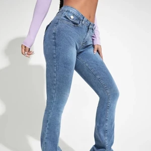 Blå bootcut jeans - Snygga blå bootcut jeans med hög midja och klassisk femficksdesign. Jeansen har en dragkedja och knapp framtill samt dekorativa bakfickor med knappar. Perfekta för en avslappnad stil.