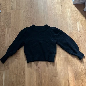 Svart stickad tröja från Gina Tricot - Säljer en snygg svart stickad tröja från Gina Tricot. Tröjan har långa ärmar och en croppad passform som ger en modern look. Perfekt för kyligare dagar och kan enkelt matchas med olika outfits.