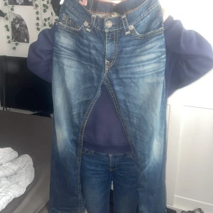 Blå jeans från True Religion - Snygga blå jeans från True Religion med klassisk femficksdesign och broderade bakfickor. De har en wash out look och är väldigt baggy men riktigt snygga. 