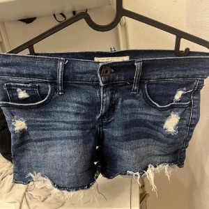 Mörkblå jeansshorts med slitningar - Snygga mörkblå jeansshorts med slitningar och fransiga kanter. Köpta secondhand. Tryck på köp nu!