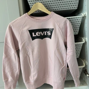 Rosa sweatshirt från Levi's - Säljer en snygg rosa sweatshirt från Levi's med deras ikoniska logga i svart på framsidan. Tröjan har långa ärmar och en rund halsringning. Perfekt för en avslappnad stil. 🩷
