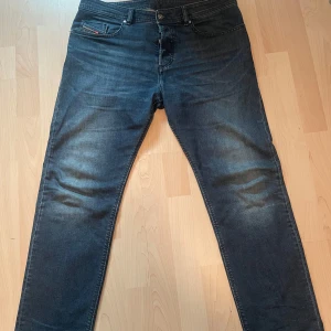 Mörkblå jeans från Diesel - Snygga mörkblå jeans från Diesel i modellen Buster. De har en tapered passform och är i storlek W33. Klassisk design med fem fickor och knappgylf. Perfekta för en stilren look. Byxorna är riktigt sköna och feta. För frågor eller funderingar, så är det bara att skriva!