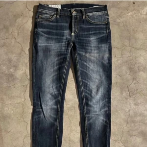 Mörkblå jeans från Dondup - Snygga mörkblå jeans från Dondup med en klassisk femficksdesign och en läderpatch baktill. Jeansen har en lätt tvättad look och kontrastsömmar som ger en cool touch. Perfekta för en avslappnad stil.
