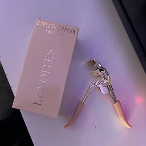 Ögonfransböjare från Lenoites - Elegant ögonfransböjare från Lenoites med en stilren design i guld och rosa. Perfekt för att ge dina fransar en vacker böj och lyft. Handtaget är bekvämt och ger ett bra grepp.