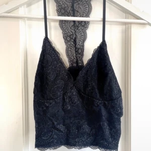 Svart spetslinne från Amisu - Säljer ett elegant svart spetslinne från Amisu. Linnet har smala axelband och en vacker spetsdetalj som sträcker sig över ryggen. Perfekt för en stilfull look.