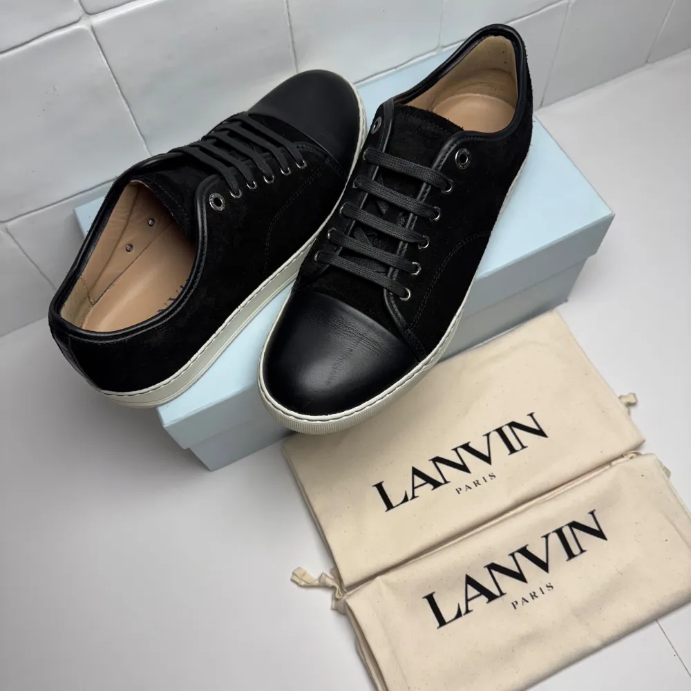 Snygga svarta sneakers från Lanvin med en stilren design. Skorna har en kombination av mocka och skinn, samt svarta snören och en vit sula. Perfekta för en trendig look. Dess är näst intill helt nya med box mm. Bara att höra av sig till oss vid minsta fundering😁. Kengät.