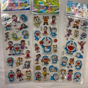 Klistermärken med Doraemon och vänner - Färgglada klistermärken med Doraemon och hans vänner i olika roliga poser. Perfekt för att dekorera anteckningsböcker, telefoner eller andra ytor. Innehåller flera ark med olika motiv. 3 år + 