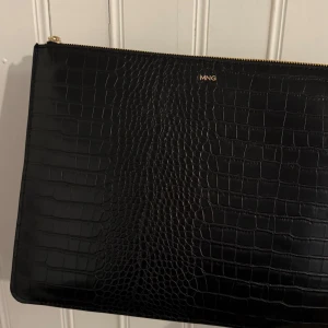 Svart kuvertväska från MNG - Elegant svart data väska från MNG med krokodilpräglat mönster och en praktisk dragkedja upptill. 