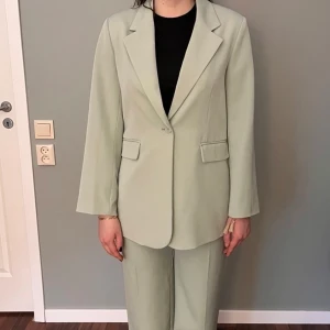Ljusgrön kostym från Bik Bok - Snygg ljusgrön kostym från Bik Bok. Kavajen är stor i storleken och passar M/L. Byxorna är sann i storleken (38). Kavajen har en klassisk design med en knapp och byxorna har hög midja med veck framtill. Perfekt för en stilren look.