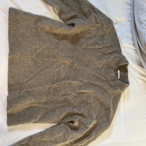 Beige stickad tröja från Gina tricot - Säljer en stilren grå stickad tröja från Gina tricot. Tröjan har en klassisk design med ribbstickade muddar vid ärmslut och nederkant. Perfekt för kyligare dagar. Storlek S