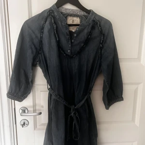 Mörkblå klänning från Lexington - Snygg mörkblå klänning från Lexington med trekvartsärm och knytband i midjan. Klänningen har en avslappnad passform och dekorativa sömmar längs ärmarna. Perfekt för en stilren look.