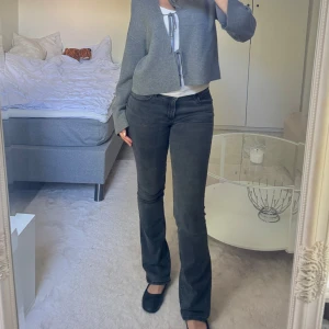 Gråa bootcut jeans från Wrangler - Säljer ett par gråa bootcut jeans från Wrangler med klassiska bakfickor och snyggt mörk tvätt. Jeansen har normal passform och är tillverkade i mjukt bomullsmaterial med lite stretch. 