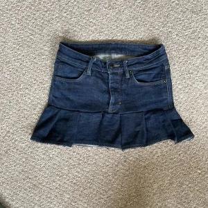 Mörkblå jeanskjol med volang - Snygg mörkblå jeanskjol från Neuw med volang nertill. Storleken står inte men skulle tro att den är xs eller lite mindre. Midjemåttet är ungefär 72 cm och kjolen är 30 cm lång. Priset kan diskuteras