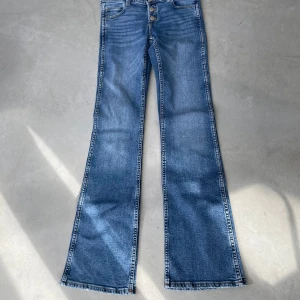 Blå bootcut jeans från Gina Tricot, tall - Snygga blå jeans från Gina Tricot med bootcut-modell och låg midja. Jeansen har tre knappar framtill, klassiska fickor och är tillverkade i mjukt denimtyg. Tall!