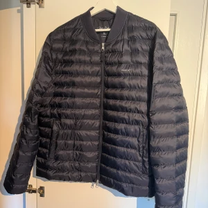 Gant höst/vinterjacka, mörkblå. **kanonskick** - Snygg pufferjacka från Gant i storlek XL. Jackan har quiltad design, dragkedja framtill och ribbade muddar vid halsen. Perfekt för kyliga dagar och enkel att matcha med olika outfits. Klassisk och stilren look. Jackan har lite tunnare foder. Den är köpt ny av mig och väldigt sparsamt använd. Jackan är i kanonskick! 