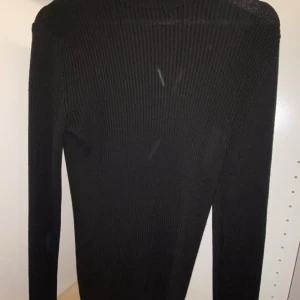 Svart ribbad polotröja från ASOS - Svart ribbad polotröja från ASOS i storlek S. Tröjan är långärmad och har en tight passform med stretchigt material. Perfekt basplagg med enkel design och hög krage som ger en clean look. Den sitter bra och passar dig som har storlek S. Skriv till mig om du har några funderingar. Den har inga defekter bara lite nopprig. 