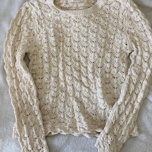 Beige stickad kofta  - Supersöt beige stickad kofta från Lindex med snyggt hålmönster och tre stora knappar vid axeln. Långärmad och i mjuk bomull, perfekt för lager på lager. Snygga vågiga kanter nertill och vid ärmslut. Passar dig som gillar en klassisk men trendig look.