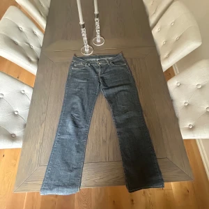 Mörkblå Victoria Beckham jeans  - Snygga mörkblå jeans från Victoria Beckham  med raka/utsvängda ben. Jeansen har guld kronor på bakfickorna som tyvärr har tappat ett par stenar men är fortfarande jätte snygga! Bra skick annars.