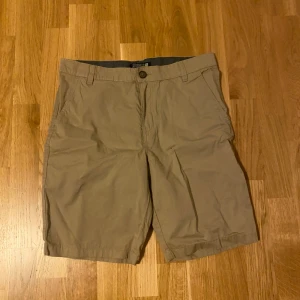 Beige shorts från H&M - Klassiska beige shorts från H&M i storlek 164. De har normal passform, midwaist och är tillverkade i mjuk bomull. Utrustade med sidofickor och bälteshällor, perfekta för varma sommardagar.