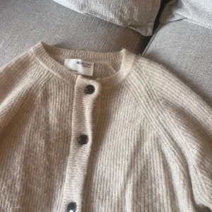 Beige stickad kofta från Selected Femme - Supermysig beige stickad kofta från Selected Femme med svarta knappar framtill. Koftan har rund halsringning och långa ärmar. Storlek S. Kan skicka fler bilder med den på!