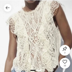 Vit spetsblus med volangdetaljer - Superfin vit blus i spets med snygga volangdetaljer på axlarna och längs framsidan. Ärmlös modell med spets och rund halsringning. Inga defekter på den då jag inte använt den så mycket, skriv för fler bilder 