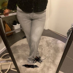 Grå bootcut jeans med hög midja - Säljer ett par snygga grå jeans med bootcut-modell och medelhögmidjad. Jeansen har klassisk femficksdesign och är tillverkade i ett mjukt denimtyg. Perfekta för dig som gillar en stilren och trendig look.