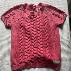 Rosa stickad tröja med snörning - Supersöt rosa stickad tröja med korta ärmar och flätstickat mönster fram. Baksidan har snygg snörningsdetalj upptill. Från odd Molly och säljs inte längre finns inte att köpa någonstans för tillfället. Står ingen storlek men skulle tippa på xxs-s. Orginalpris runt 1200