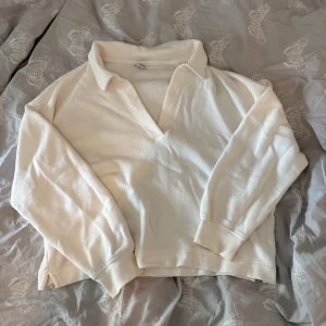 Vit v-ringad tröja Old Navy - Vit långärmad tröja från Old Navy i mjuk bomullsmix. Tröjan har en snygg v-ringning med krage och avslappnad passform. 