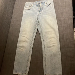 Levi's 501 ljusblå jeans 24/26 - Klassiska Levi's 501 jeans i ljusblå tvätt med raka ben och knappgylf. Jeansen har fem fickor, snyggt vintage-inspirerat utseende och är tillverkade i 100% bomull. Perfekta för dig som gillar tidlös denimstil.