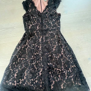 Svart spetsklänning från H&M - Supersnygg svart spetsklänning från H&M med nude-färgad underklänning. Klänningen har v-ringning, korta ärmar och dragkedja i ryggen. Blommigt spetsmönster och lätt utställd kjol ger en romantisk vibe. Perfekt för dig som vill sticka ut lite extra!