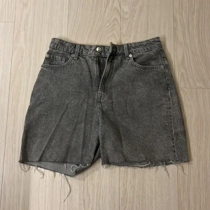Grå jeansshorts med rå kant - Säljer ett par grå jeansshorts. Klassisk femficksmodell med bälteshällor och dragkedja. Stilen är loose och avslappnad, perfekt för en chill look. Materialet är denim och färgen har en tvättad, lite vintage känsla. Osäker på storlek och märke men skulle gissa 36/S och HM.