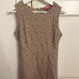 Beige spetsklänning från Indiska - Supersöt beige kortklänning från Indiska med vackert spetsmönster över hela klänningen. Ärmlös modell med rund halsringning, perfekt för sommarens alla tillfällen. Snygg och feminin look!