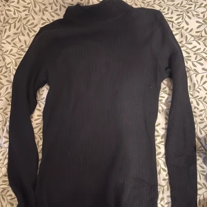 Ribbad polotröja svart & grön - Två ribbade polotröjor i svart och mörkgrönt. Båda har lång ärm och tight passform, perfekta att styla med jeans eller kjol. Materialet är stretchigt och mjukt, vilket gör dem riktigt sköna att bära. Snygg basic som funkar till många olika looks. 1 för 40kr två för 70kr