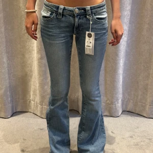 Lågmidjade bootcut jeans  - Snygga ljusblå jeans från Gina Tricot i modellen 14+ real low jeans. De har låg midja, bootcut-ben och klassiska fickor både fram och bak. Jeansen är i stretchigt denim och har en trendig tvättad look. Helt nya! Högre pris pga slutsålda, Midjemått: 32cm tvärsöver (stretchiga), innerben: 86 cm