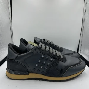 Valentino Rockrunner - Svarta/blåa Valentino Rockrunner sneakers med alla nitar på sidorna och hälen. Dem är storlek 40/41 och är köpte på The Real Real, kvitto och dustbag finns med ifrån The Real Real. Nypris ligger på ca 7000kr, mitt pris 1200kr.