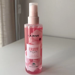 La Rive Crazy in Love Body Mist - Fräsch rosa body & hair mist från La Rive med blommigt motiv på flaskan. Innehåller vitamin E och provitamin B5, vegansk formula. Praktisk sprayflaska i plast, perfekt att ha med i väskan för en snabb uppfräschning.