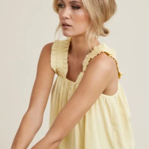 Gul linnetopp  - Supersöt ljusgul linnetopp med breda axelband och volangdetaljer. 