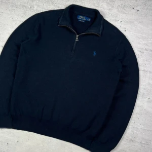 Mörkblå half zip tröja Polo Ralph Lauren - Snygg mörkblå tröja från Polo Ralph Lauren i mjuk pima bomull. Klassisk modell med half zip och broderad logga på bröstet. Långärmad med ribbade muddar och krage. Perfekt för lager-på-lager och stilren look.