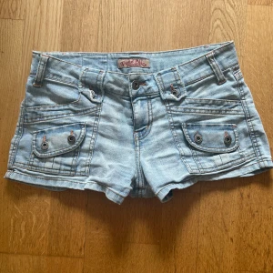 Vintage jeansshorts  - Snygga ljusblå jeansshorts från Paris Blues med flera fickor och coola knappdetaljer både fram och bak. Med låg midja och korta ben. 