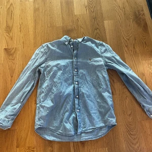 Blå skjorta från Polo Ralph Lauren - Klassisk blå skjorta från Polo Ralph Lauren med lång ärm och knappar framtill. Skjortan har en liten broderad logga på bröstet och är tillverkad i mjuk bomull. Perfekt för en avslappnad men ändå stilren look.har mycket saker att göra i sommar så kom med bud 